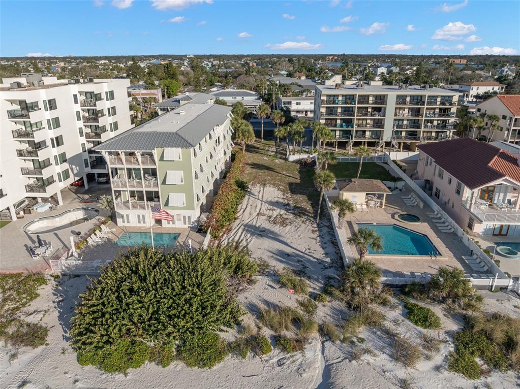 An aerial view shows a vacant sandy lot situated between two multi-story residential buildings — 1306 GULF BOULEVARD, INDIAN ROCKS BEACH, FL
