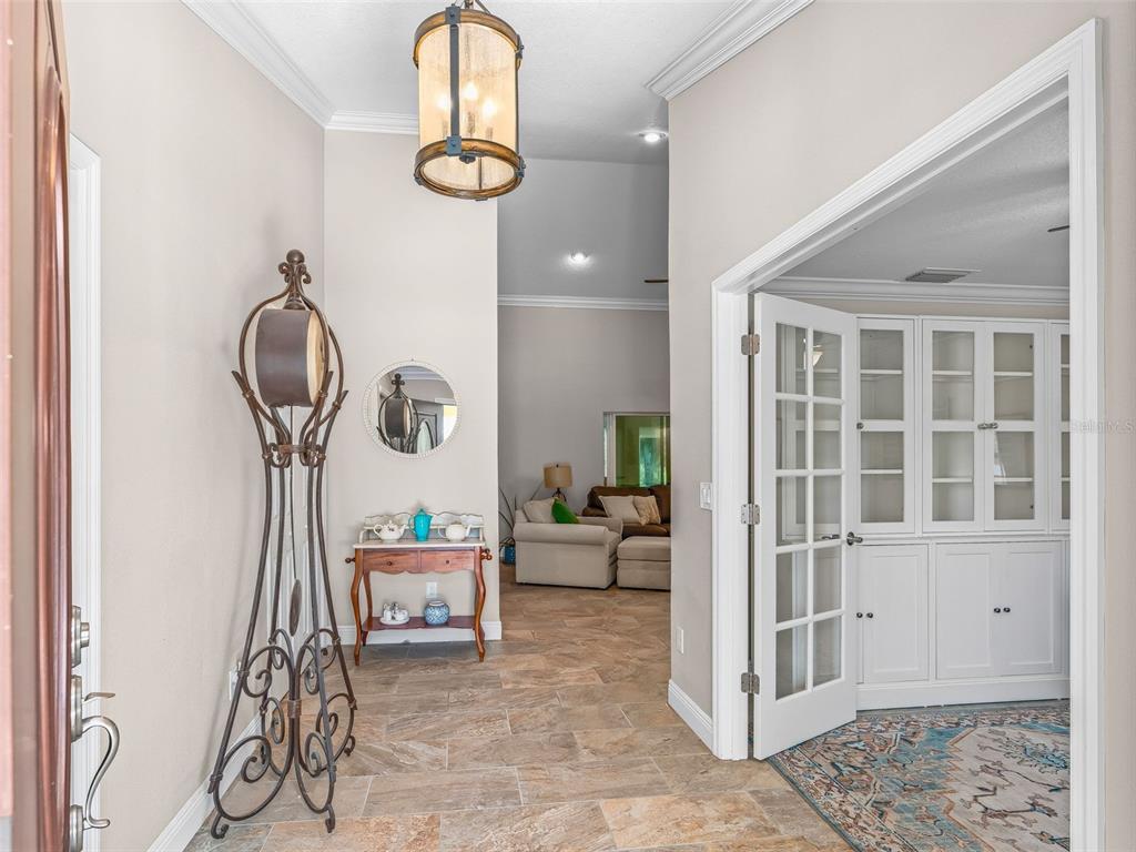 An entryway features tile flooring, a decorative metal stand, and a view into a living room — 5331 GROVE MANOR, LADY LAKE, FL