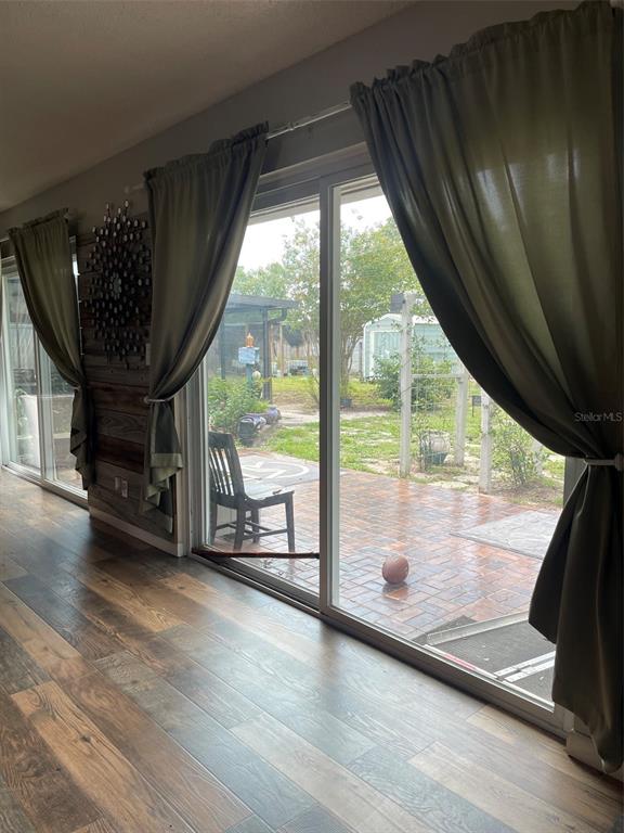 A room with wood-look flooring and sliding glass doors opening to a brick patio — 1601 STEPHENS ROAD, RUSKIN, FL