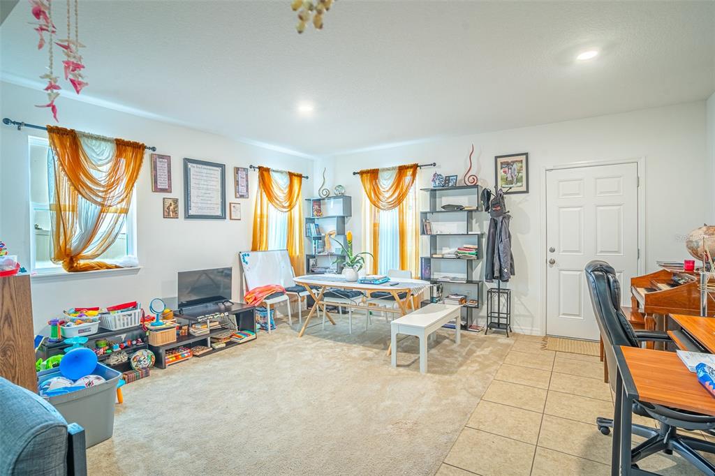 A multi-purpose room features carpeted and tiled flooring, a dining table, shelving, and a desk — 15107 ZENITH AVENUE, MASCOTTE, FL