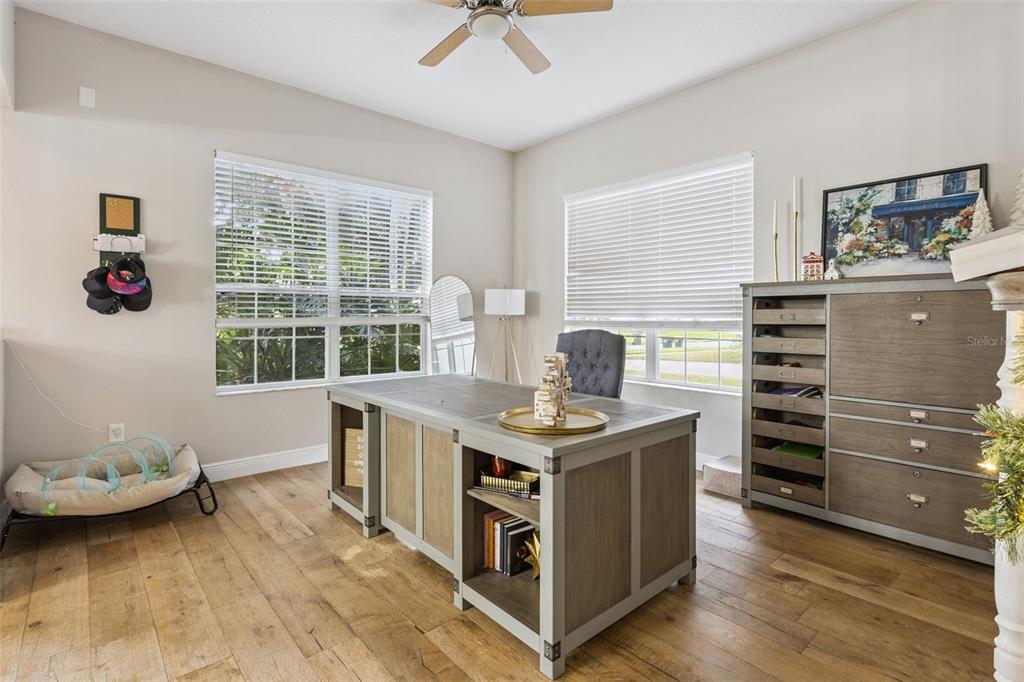 A home office features a large wooden desk, a gray chair, and light wood flooring — 3443 TUMBLING RIVER DRIVE, CLERMONT, FL
