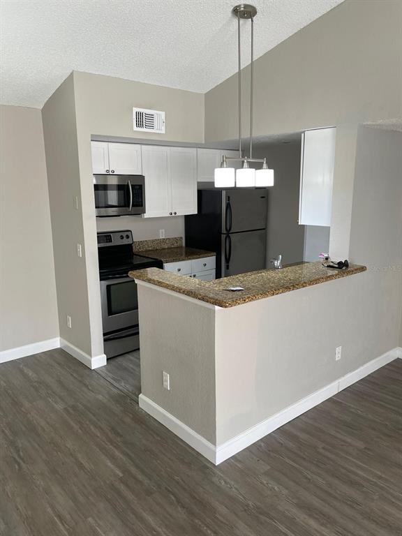 A kitchen features white cabinets, stainless steel appliances, granite countertops, and a breakfast bar — 5140 CONROY ROAD UNIT 35, ORLANDO, FL