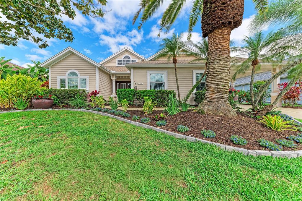 A single-story tan house with a palm tree in the front yard and landscaping — 4735 SPINNAKER DRIVE, BRADENTON, FL