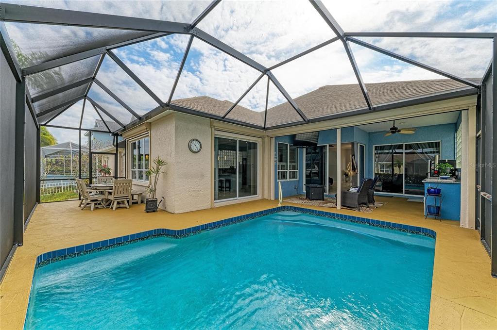 A swimming pool sits on a yellow deck inside a screened-in lanai area — 4735 SPINNAKER DRIVE, BRADENTON, FL
