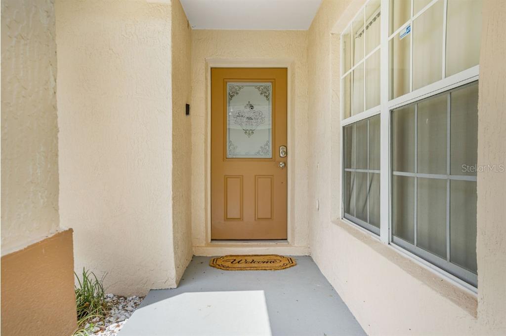 A tan front door with a glass insert sits at the entrance of a home — 2606 LUISENO WAY, KISSIMMEE, FL