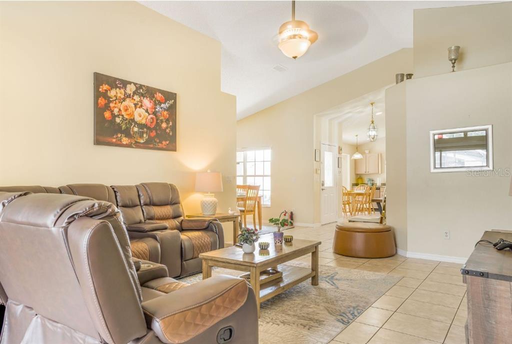 A living room with tile floors, a brown leather sofa, and a wooden coffee table — 2606 LUISENO WAY, KISSIMMEE, FL