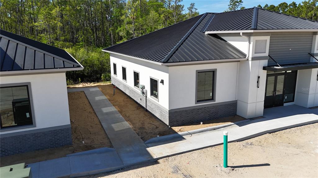 An exterior view of two modern commercial buildings with metal roofs and concrete walkways — 80 EXCHANGE LOOP LOOP UNIT 2, PALM COAST, FL