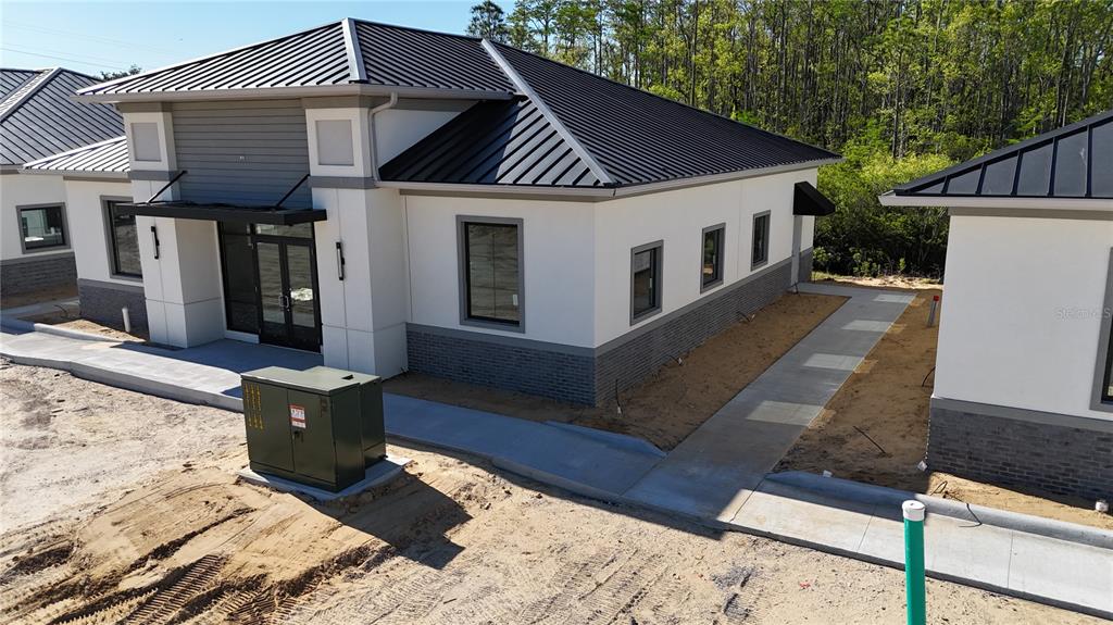 An exterior view of a modern commercial building with a metal roof and concrete walkway — 80 EXCHANGE LOOP LOOP UNIT 2, PALM COAST, FL