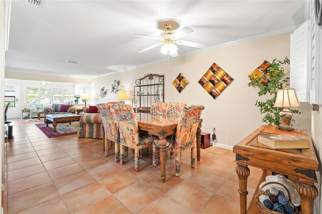 A dining area with a wooden table and patterned chairs sits on a tiled floor — 19029 US HIGHWAY 19 UNIT 25D, CLEARWATER, FL