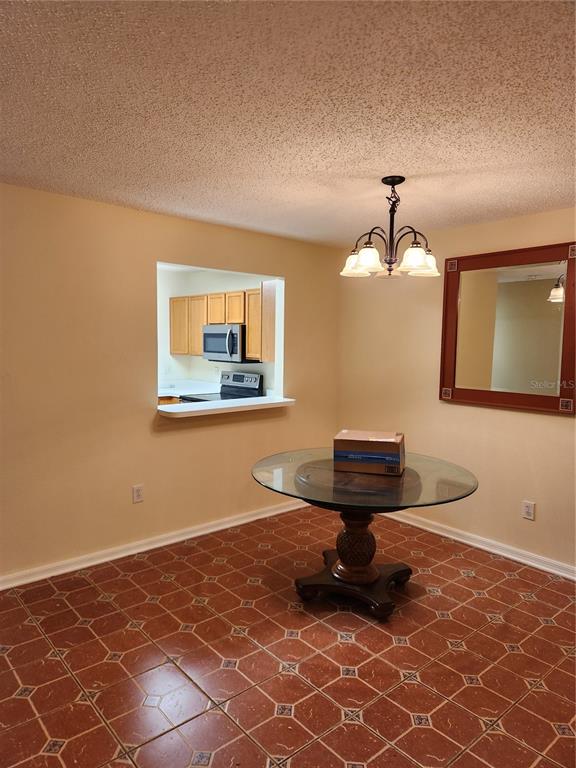 A dining room features a glass-topped pedestal table, a chandelier, and terracotta-colored floor tiles — 10815 BRICKSIDE COURT, RIVERVIEW, FL