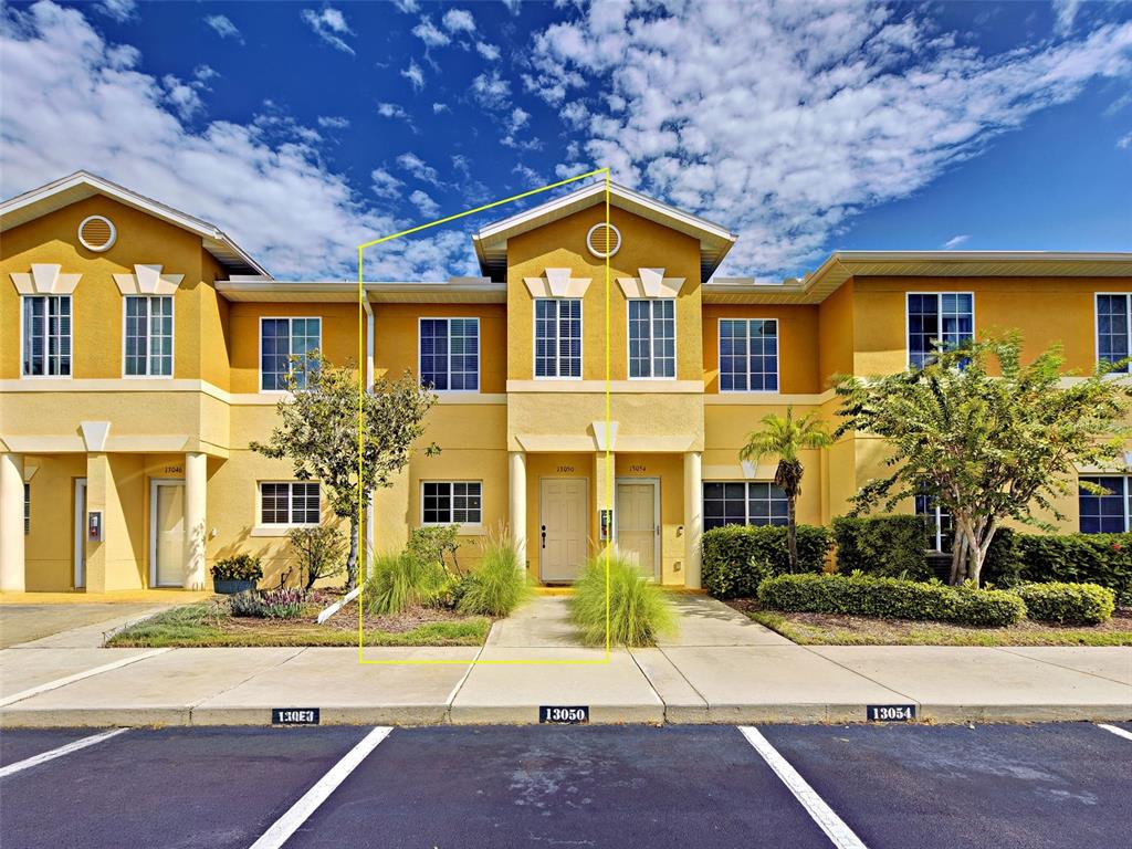 A yellow two-story townhouse exterior features a central entrance with a small front yard — 13050 TIGERS EYE DRIVE, VENICE, FL