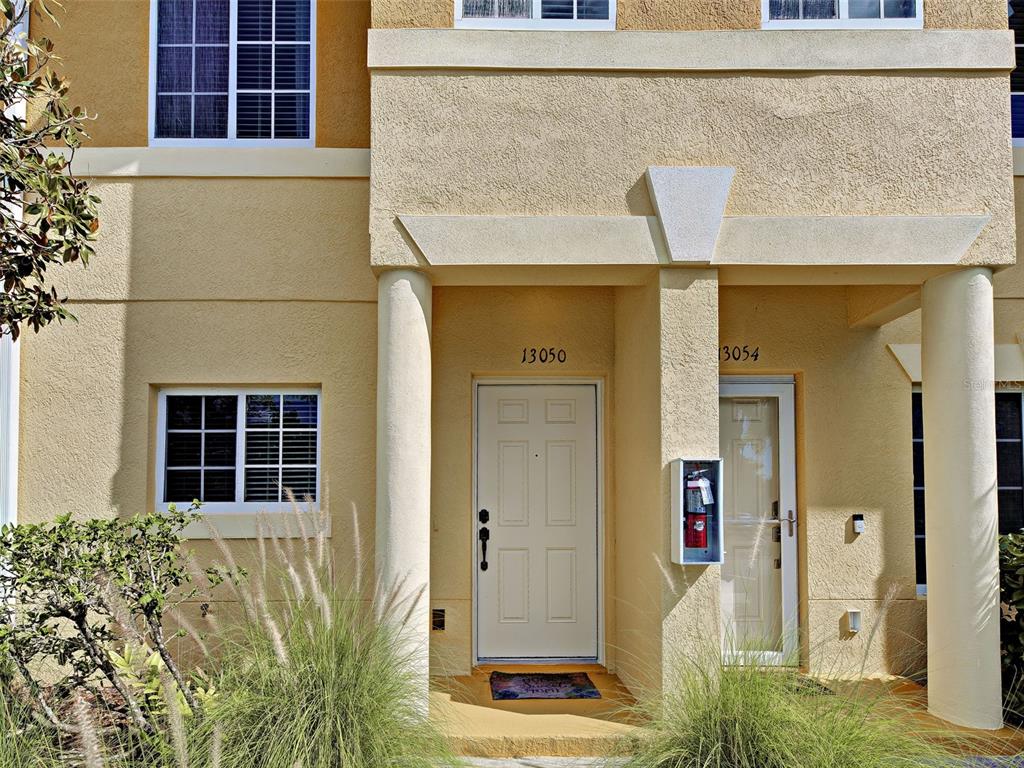 The exterior of a two-story tan stucco building features two front doors and white columns — 13050 TIGERS EYE DRIVE, VENICE, FL