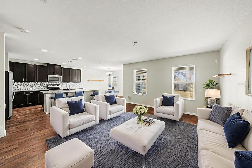 An open-concept living room features a kitchen with dark cabinets and a white sofa set — 10233 NEWMINSTER LOOP, RUSKIN, FL
