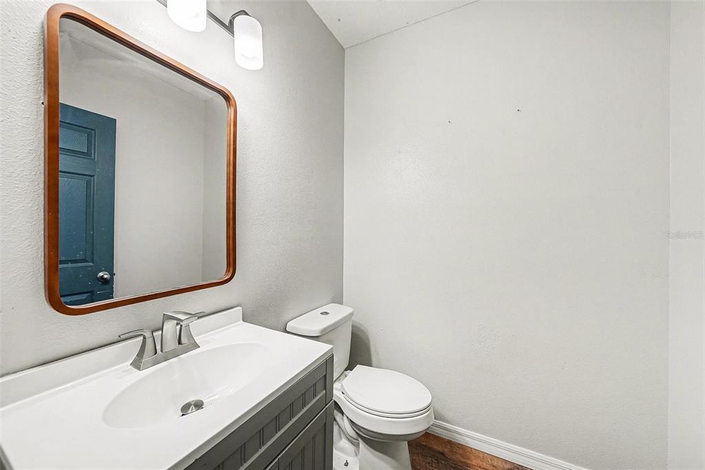 A small bathroom features a gray vanity, a rectangular mirror, and a white toilet — 10233 NEWMINSTER LOOP, RUSKIN, FL
