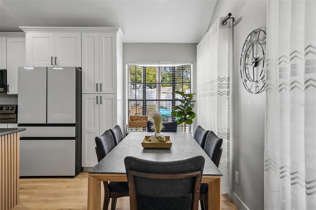 A dining room features a gray rectangular table, dark chairs, white cabinetry, and a window — 3376 SHORNCLIFFE LANE, PALM HARBOR, FL