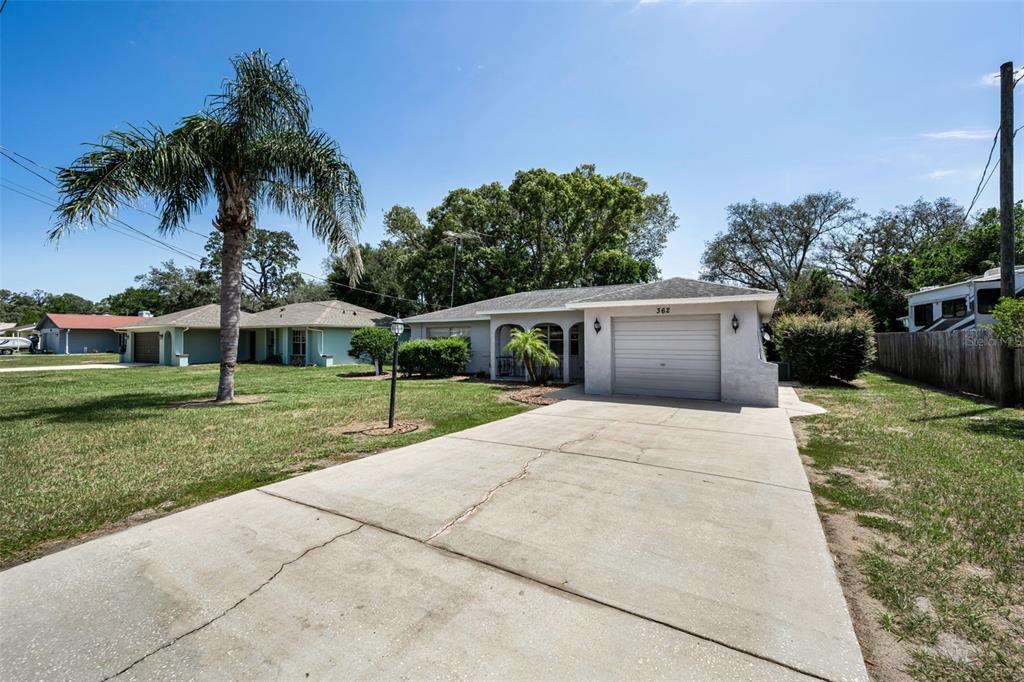 The exterior of a single-story house features a white stucco facade, arched entryway, and garage — 362 PORTLAND AVENUE, SPRING HILL, FL