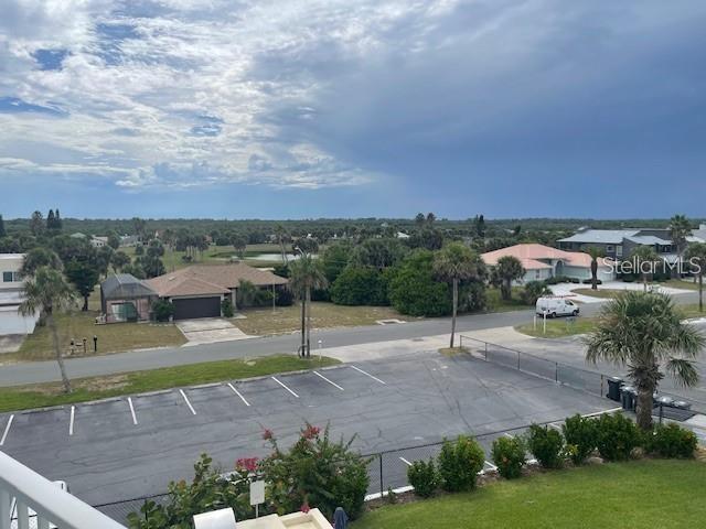 An elevated view shows a parking lot, residential houses, and palm trees under a cloudy sky — 3510 S OCEAN SHORE BOULEVARD UNIT 215, FLAGLER BEACH, FL
