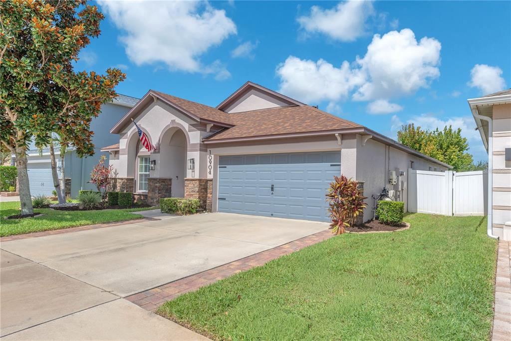 A single-story house with a beige stucco exterior, a two-car garage, and a paved driveway — 10904 RAINBOW PYRITE DRIVE, WIMAUMA, FL