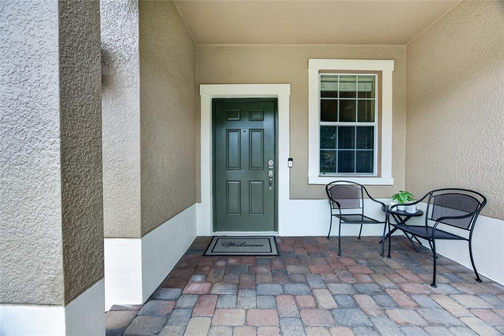 A front porch features a green door, a window, and two chairs on a paved floor — 10709 SAVANNAH LANDING CIRCLE, ORLANDO, FL