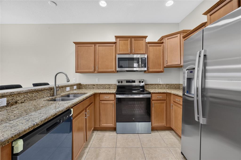 A kitchen features light wood cabinets, granite countertops, and stainless steel appliances — 10709 SAVANNAH LANDING CIRCLE, ORLANDO, FL