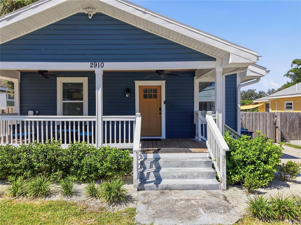 A blue house with a white porch, wooden front door, and concrete steps — 2910 N OLA AVENUE, TAMPA, FL