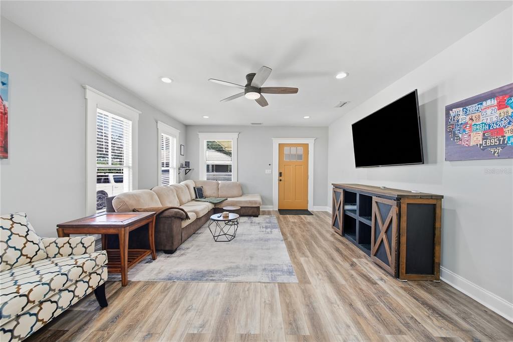 A living room features a sectional sofa, a television, a wooden console, and light flooring — 2910 N OLA AVENUE, TAMPA, FL