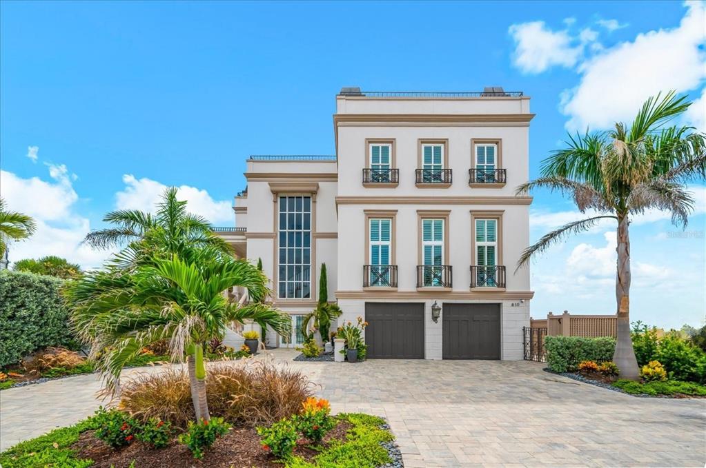 A grand foyer features a curved staircase with a patterned runner and large floor-to-ceiling windows — 810 ELDORADO AVENUE, CLEARWATER BEACH, FL