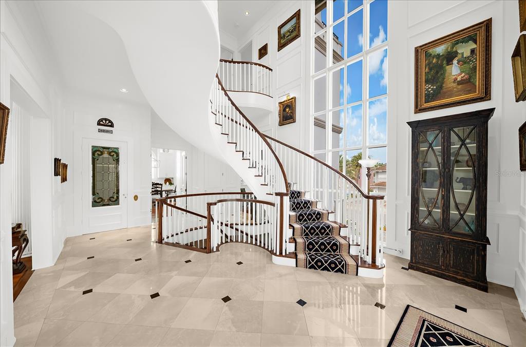 A spacious living room features parquet wood floors, white columns, and large windows overlooking the ocean — 810 ELDORADO AVENUE, CLEARWATER BEACH, FL