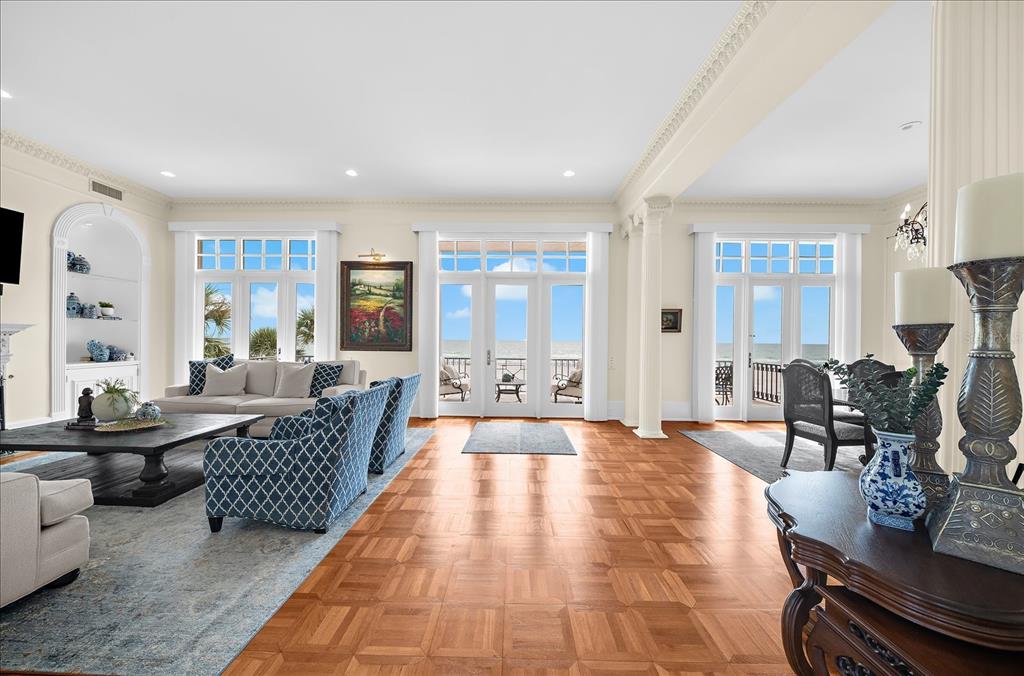 A living room features a fireplace, built-in shelving, blue patterned furniture, and ocean-view glass doors — 810 ELDORADO AVENUE, CLEARWATER BEACH, FL