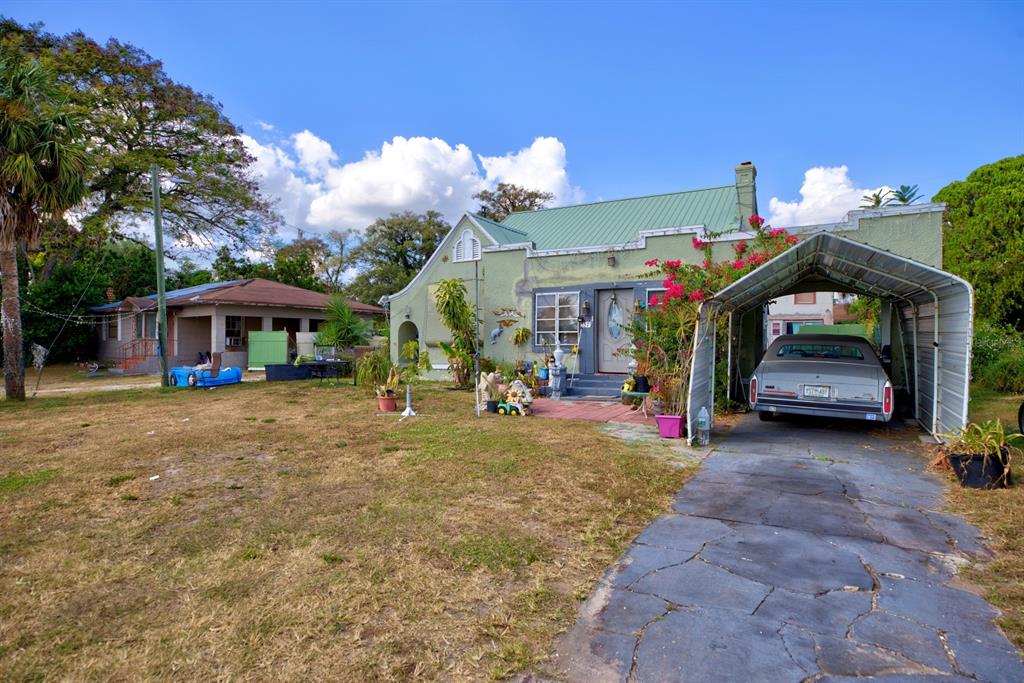 A light green house with a metal roof, a carport, and a car in the driveway — 2577 LAKE LILLIAN DRIVE, AVON PARK, FL