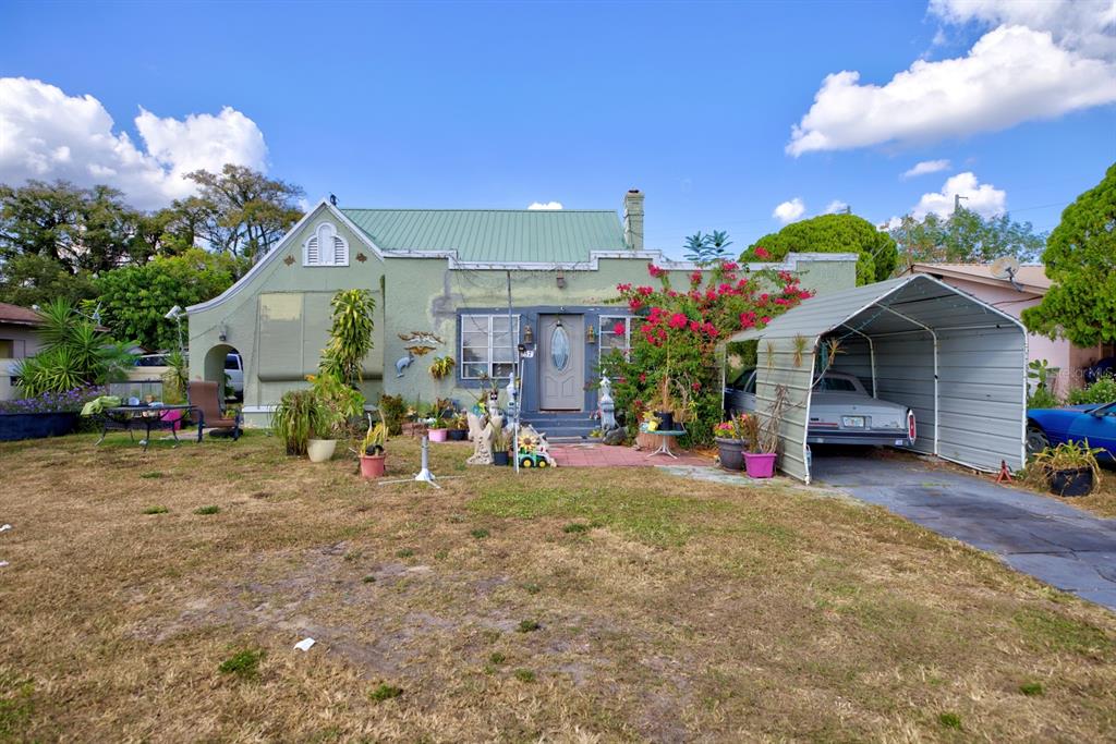A single-story green house with a metal roof, a front carport, and a dry lawn — 2577 LAKE LILLIAN DRIVE, AVON PARK, FL