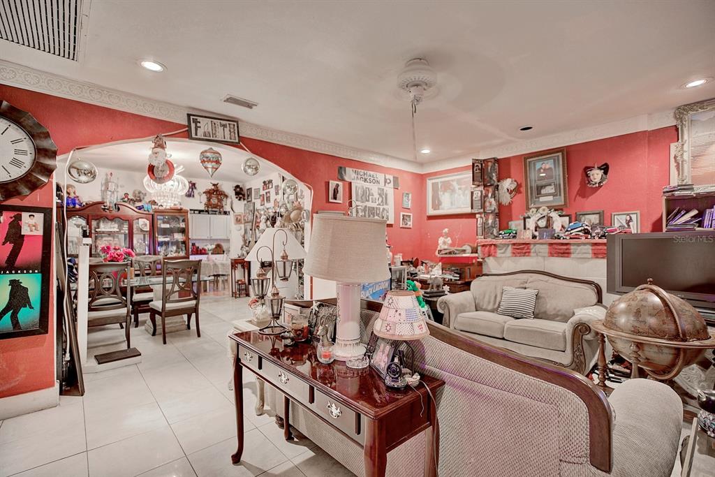 A living room and dining area feature red walls, tile flooring, and numerous decorative items — 2577 LAKE LILLIAN DRIVE, AVON PARK, FL