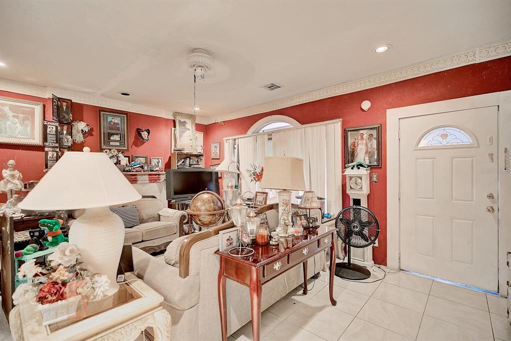 A living room with red walls, tile flooring, a white front door, and various decor — 2577 LAKE LILLIAN DRIVE, AVON PARK, FL