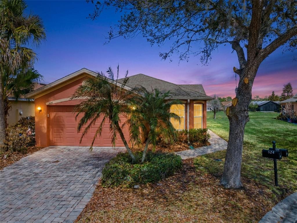 An aerial view shows three suburban houses with paved driveways situated near a golf course pond — 524 MURANO DRIVE, POINCIANA, FL