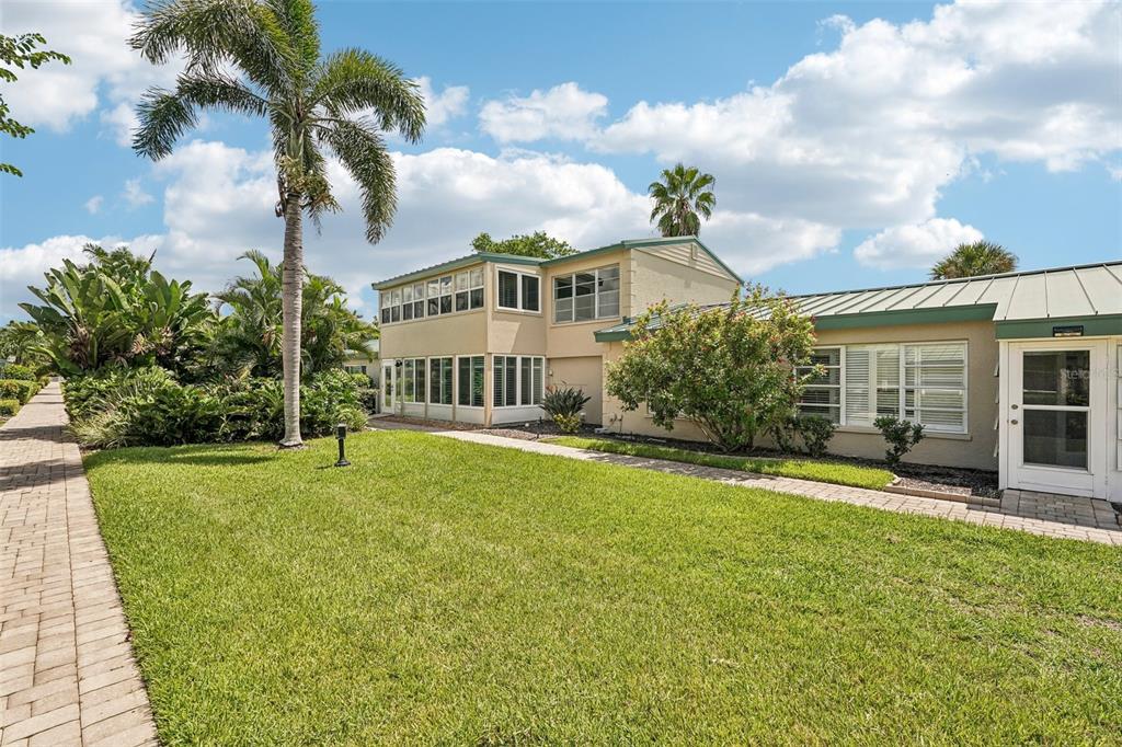 A two-story house with a green metal roof, white trim, and a palm tree outside — 5860 MIDNIGHT PASS ROAD UNIT 23, SARASOTA, FL