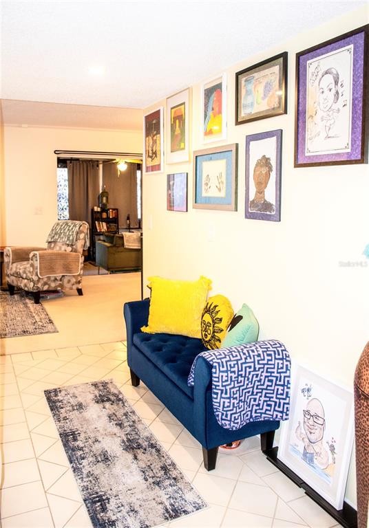 A blue tufted bench sits in a hallway with framed art on the wall — 155 FALLWOOD STREET, FERN PARK, FL