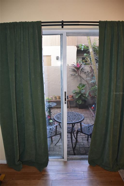 A sliding glass door opens to a small brick patio with outdoor furniture and plants — 155 FALLWOOD STREET, FERN PARK, FL