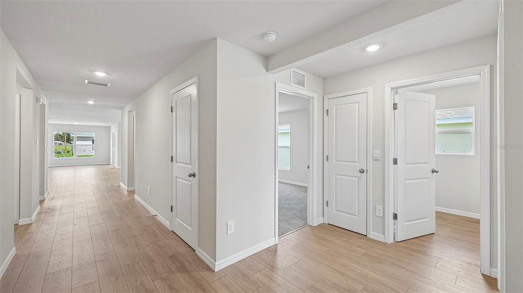 A modern kitchen features white cabinets, a central island, and light wood-look flooring — 17616 WHISKEY CREEK TRAIL, PARRISH, FL