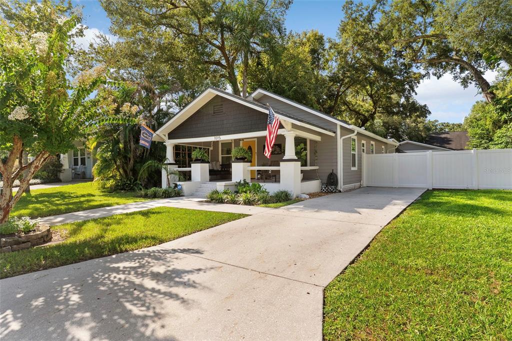 A gray bungalow with a front porch, white columns, and a concrete driveway — 1015 E CRAWFORD STREET, TAMPA, FL