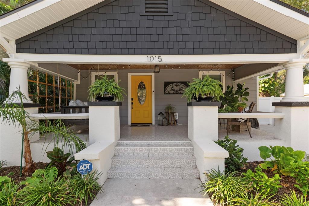 A front porch with a yellow door, white columns, and patterned tile steps — 1015 E CRAWFORD STREET, TAMPA, FL