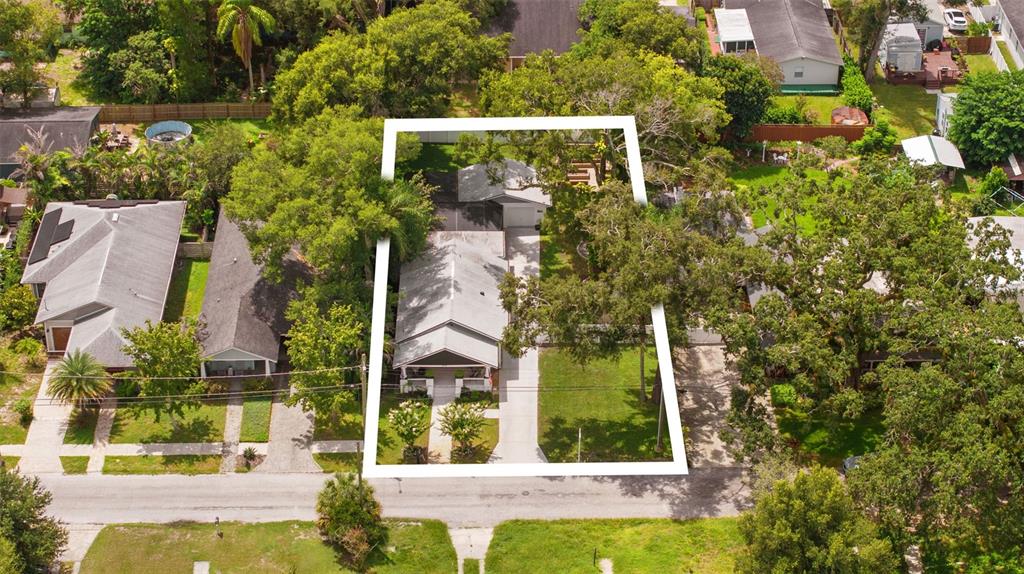 An aerial view shows a single-story house with a driveway and trees on a lot — 1015 E CRAWFORD STREET, TAMPA, FL