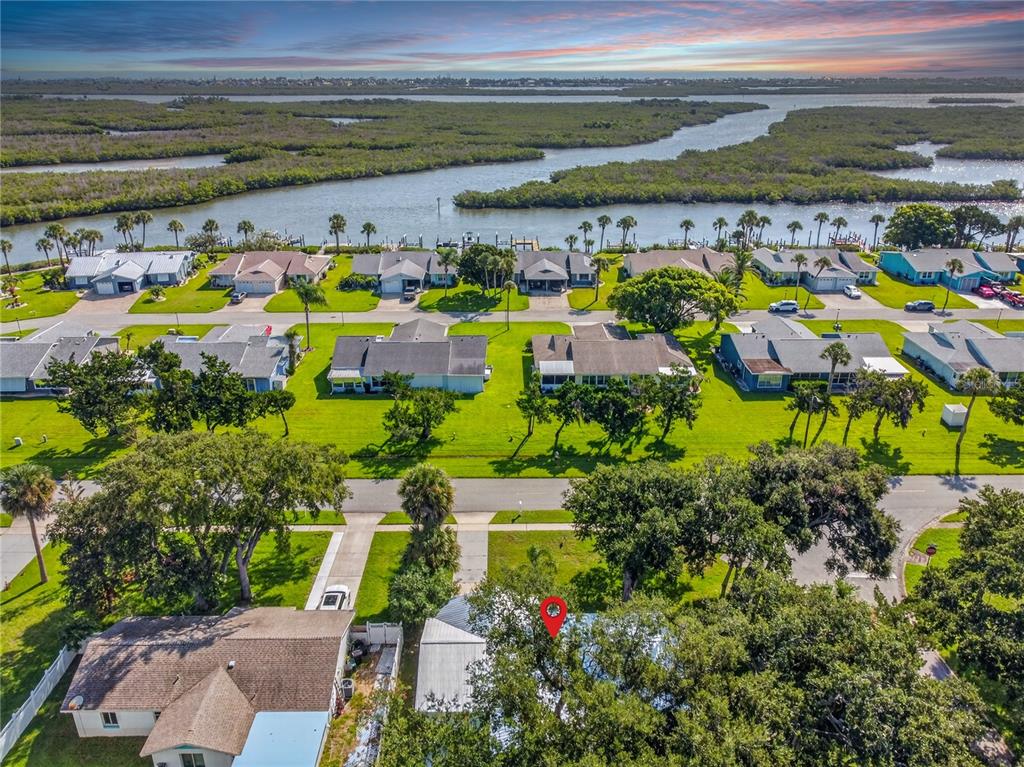 An aerial view shows a residential neighborhood with houses, green lawns, and a nearby waterway — 5464 RIVERSIDE DRIVE, PORT ORANGE, FL