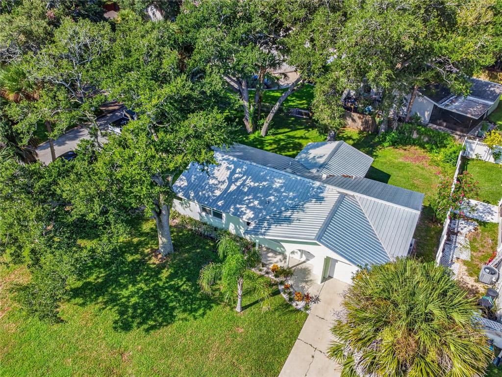 An aerial view of a single-story house with a metal roof and a large front yard — 5464 RIVERSIDE DRIVE, PORT ORANGE, FL