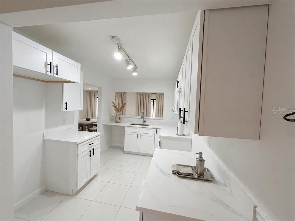 A white kitchen features shaker-style cabinets, marble-look countertops, and tile flooring — 705 TEAL LANE, ALTAMONTE SPRINGS, FL