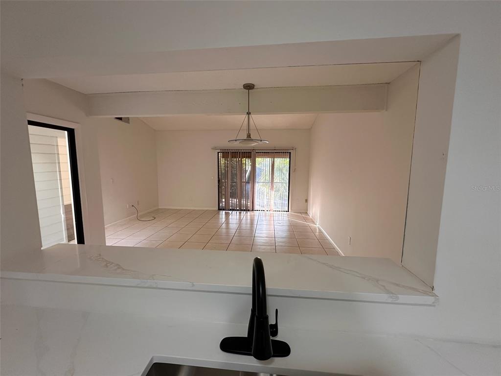 A kitchen pass-through window overlooks a tiled living area with a sliding glass door — 705 TEAL LANE, ALTAMONTE SPRINGS, FL