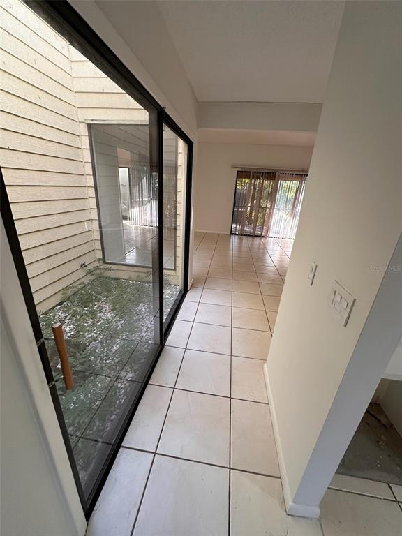 A tiled hallway leads to a living area with sliding glass doors overlooking an outdoor atrium — 705 TEAL LANE, ALTAMONTE SPRINGS, FL