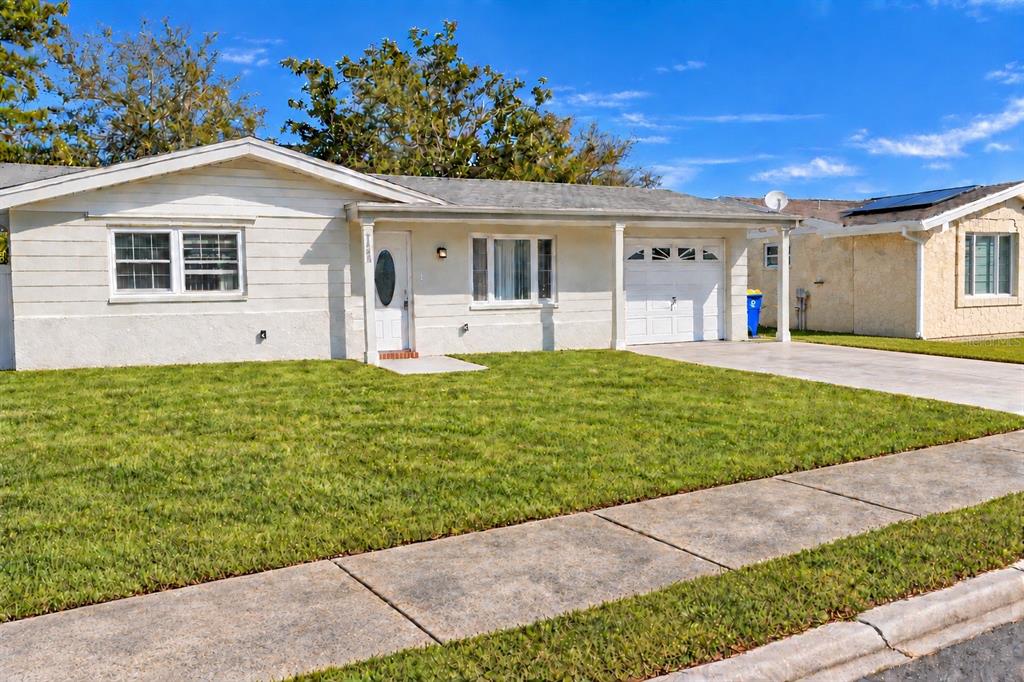A single-story house with a white garage door, a covered porch, and a green lawn — 4033 NEWCASTLE DRIVE, NEW PORT RICHEY, FL