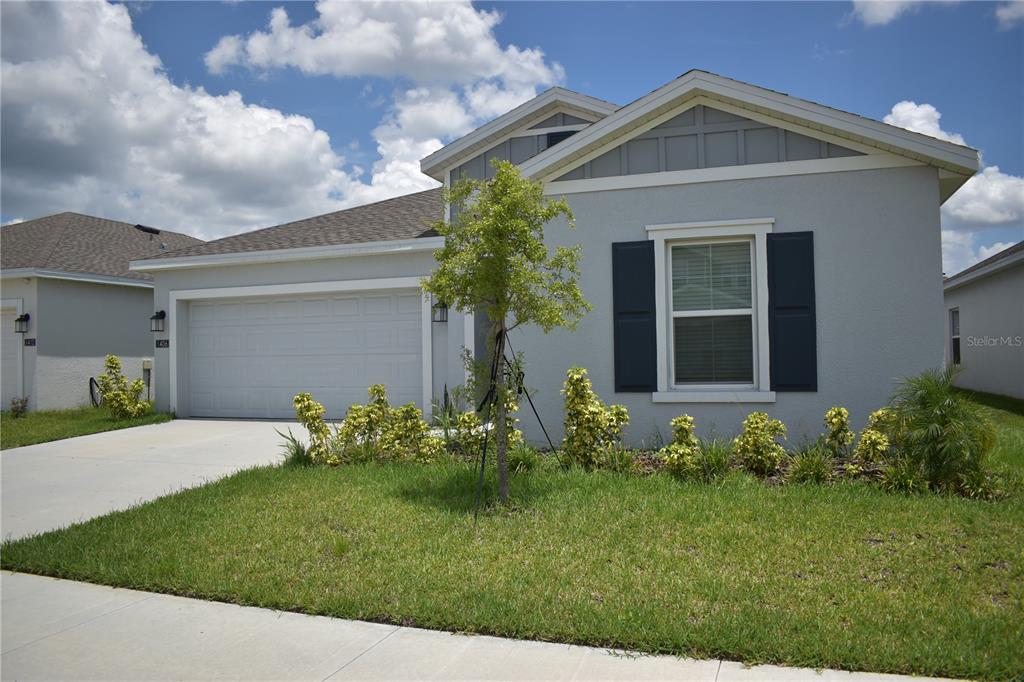 A single-story house with a two-car garage, gray siding, and a small front yard — 1406 DEEPWATER CIRCLE, EAGLE LAKE, FL