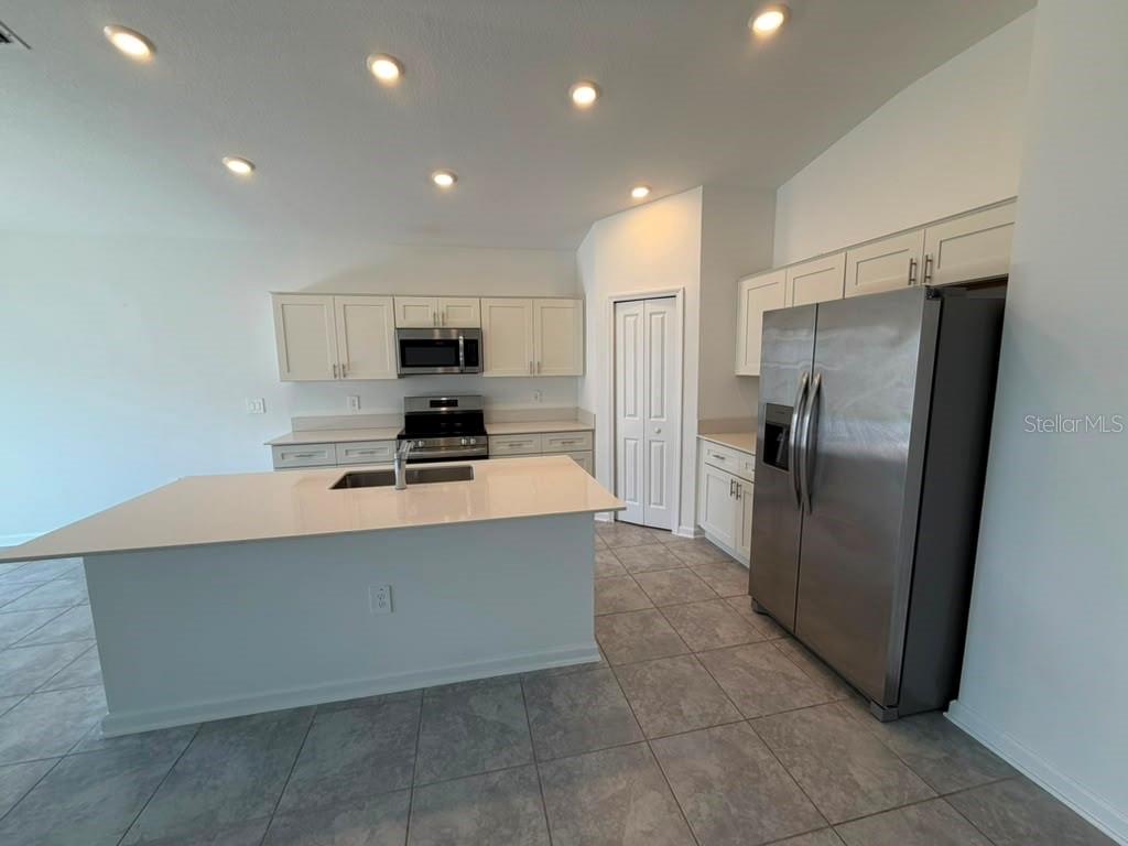 A kitchen with white cabinets, stainless steel appliances, a center island, and tile flooring — 1406 DEEPWATER CIRCLE, EAGLE LAKE, FL