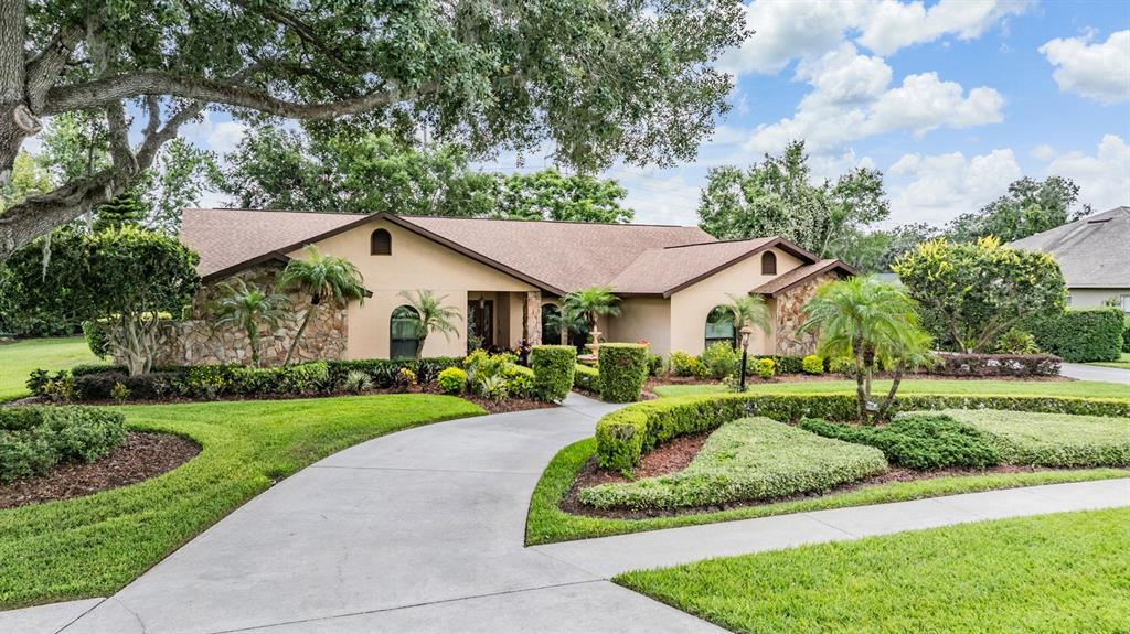 A single-story house with a stone facade, a curved driveway, and manicured landscaping — 13203 SPINDLEWYCK COVE, RIVERVIEW, FL